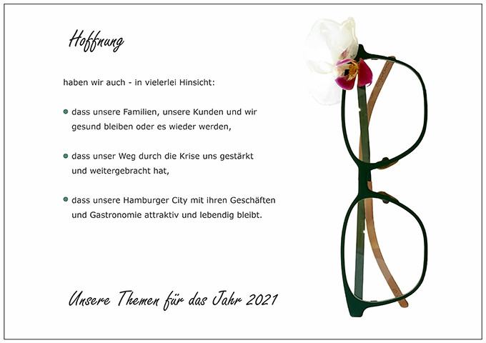 Der BELLEVUE-Wunsch Hoffnung mit einer grünen Brille von Orgreen und einer angesteckten Blüte.