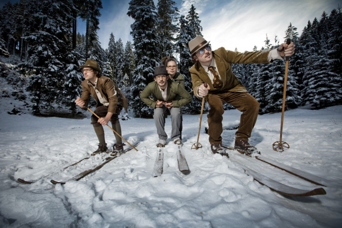 Roland und Bernhard Wolf mit ihren Mitgründern in Vintage-Skiausrüstung am verschneiten Berg.