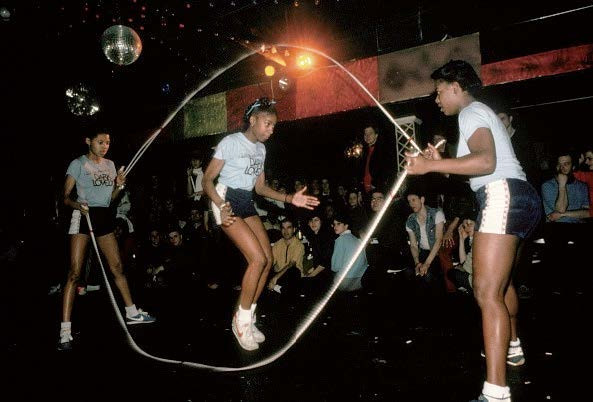 3 Mädchen in Sport-Outfit mit einem doppelten Springseil in einer Springseil-Figur mit dem Namen Double Dutch. 