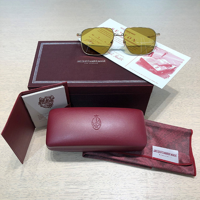 Arrangement der Jacques Marie Mage Sonnenbrille Sexton mit ihrer Brillenbox und dem Umkarton in bordeaux-rot, dem Mikrofasertuch und der Zertifikat.