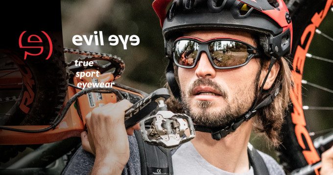 Ein Mountainbiker mit schützender evil eye Sportbrille und Helm trägt sein Bike.