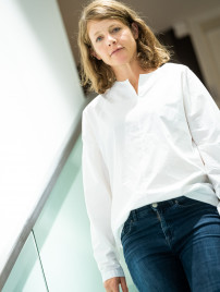 Veronika Wildgruber in Jeans und weißer Bluse auf der Treppe im Geschäft von BELLEVUE