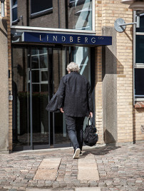 Henrik Lindberg, ehemaliger Inhaber des Unternehmens Lindberg, geht mit einer großen Tasche in der Hand zur Eingangstür der Lindberg Manufaktur.