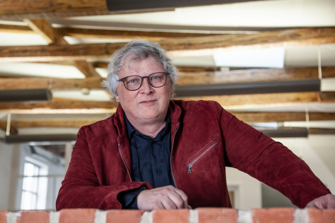 Henrik Lindberg mit roter Jacke und havannafarbener Acetatbrille auf einer Galerieebene in Lindberg Headquarter.