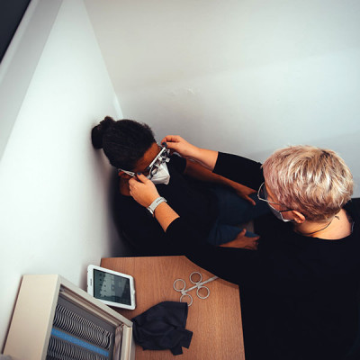 Augenoptiker mit Kundin beim Einstellen einer Sehtest-Prüfbrille im Augenprüfraum bei BELLEVUE.