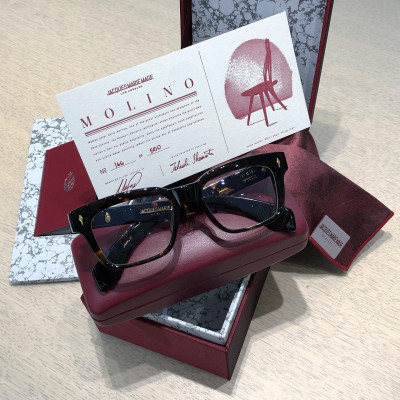 Arrangement der edlen Verpackung und des Zertifikats einer Jacques Marie Mage Brille im typischen bordeaux-rot.