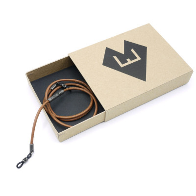 Hellbraune Leder-Brillenkette aufgerollt in einer kleinen Pappbox mit dem Logo von von Ernst.